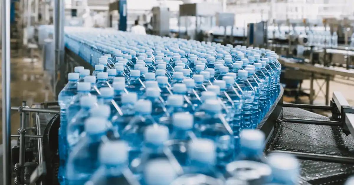 Bottled water moving along a conveyor belt in a continuous flow production line.