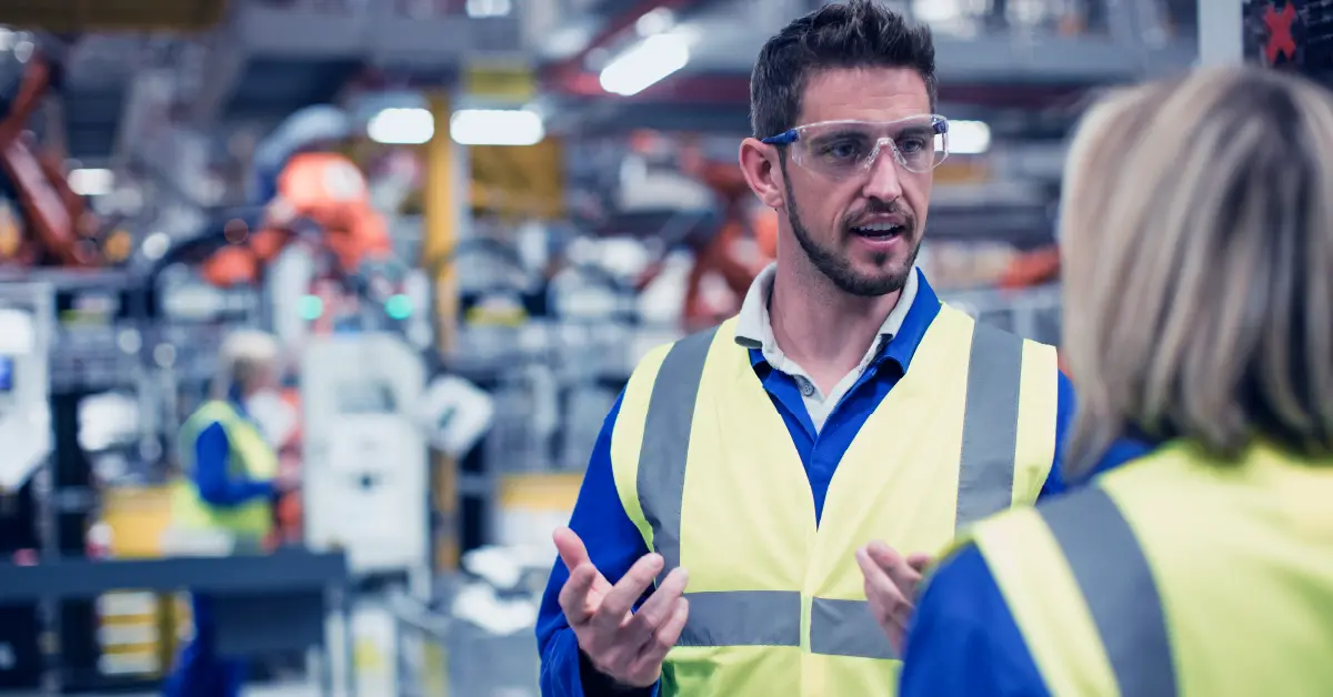 Manufacturing team discussing A3 continuous improvement strategies on factory floor